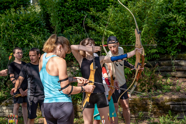 Groupe de personnes équipé d'arcs et de flèches sur un atelier tir à l'arc au flower camping du Lac du Causse