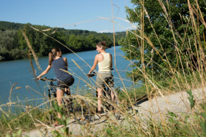 2 femmes sur un vélo de dos avec vue sur le Lac du Causse