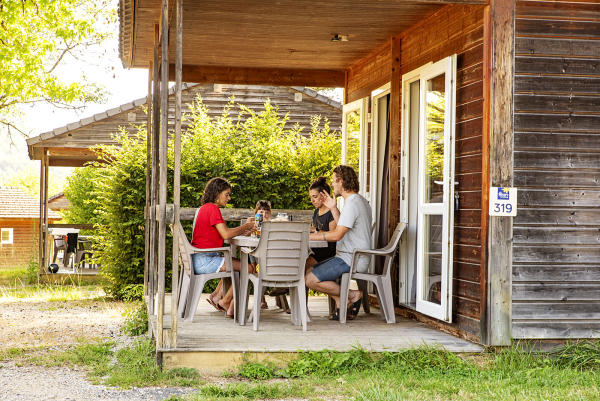 hebergements camping du lac du causse, une famille sur la terrasse d'un chalet en bois